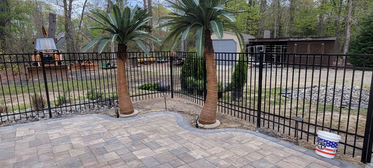 Paver patio and palms behind an iron fence